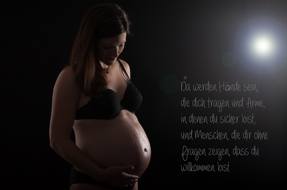 schwangere Frau beim Schwangerschafts-Shooting hält Hand auf ihren Bauch