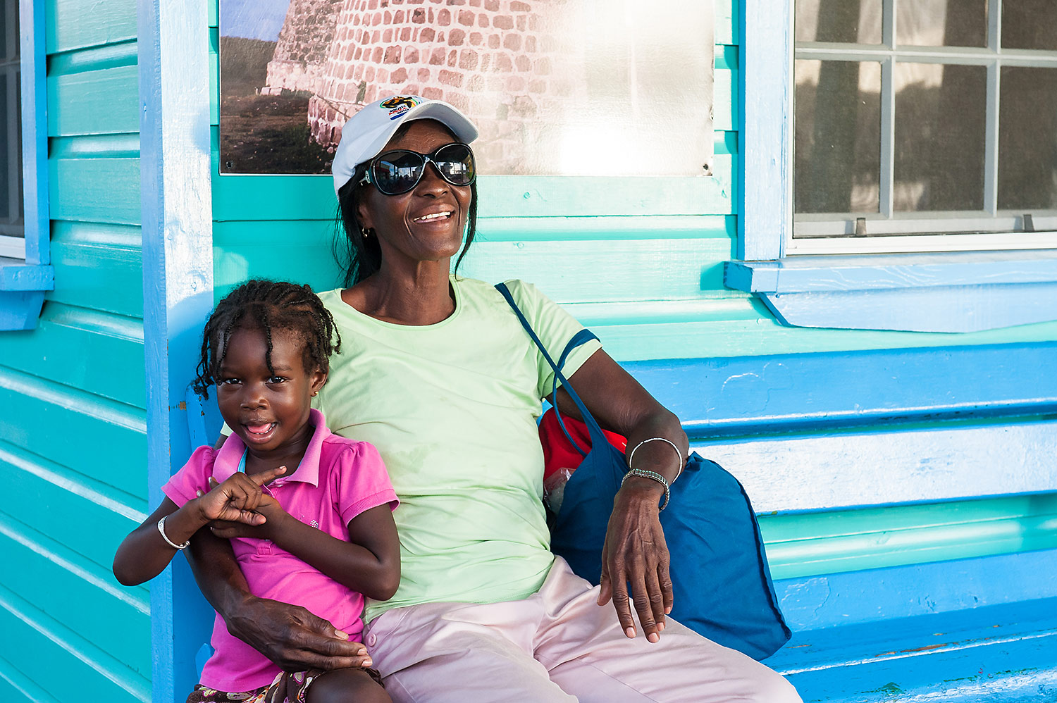 Farbige Frau mit Kind sitzt auf einer bunten Bank