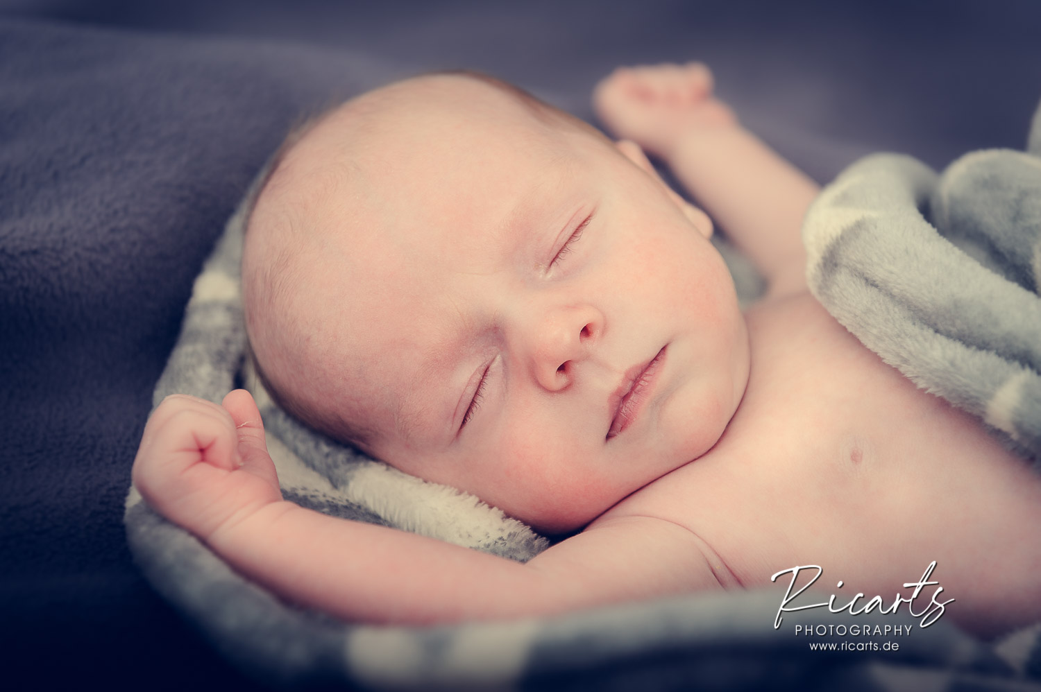 Newborn-Baby-schlafend-auf-grauer-Decke