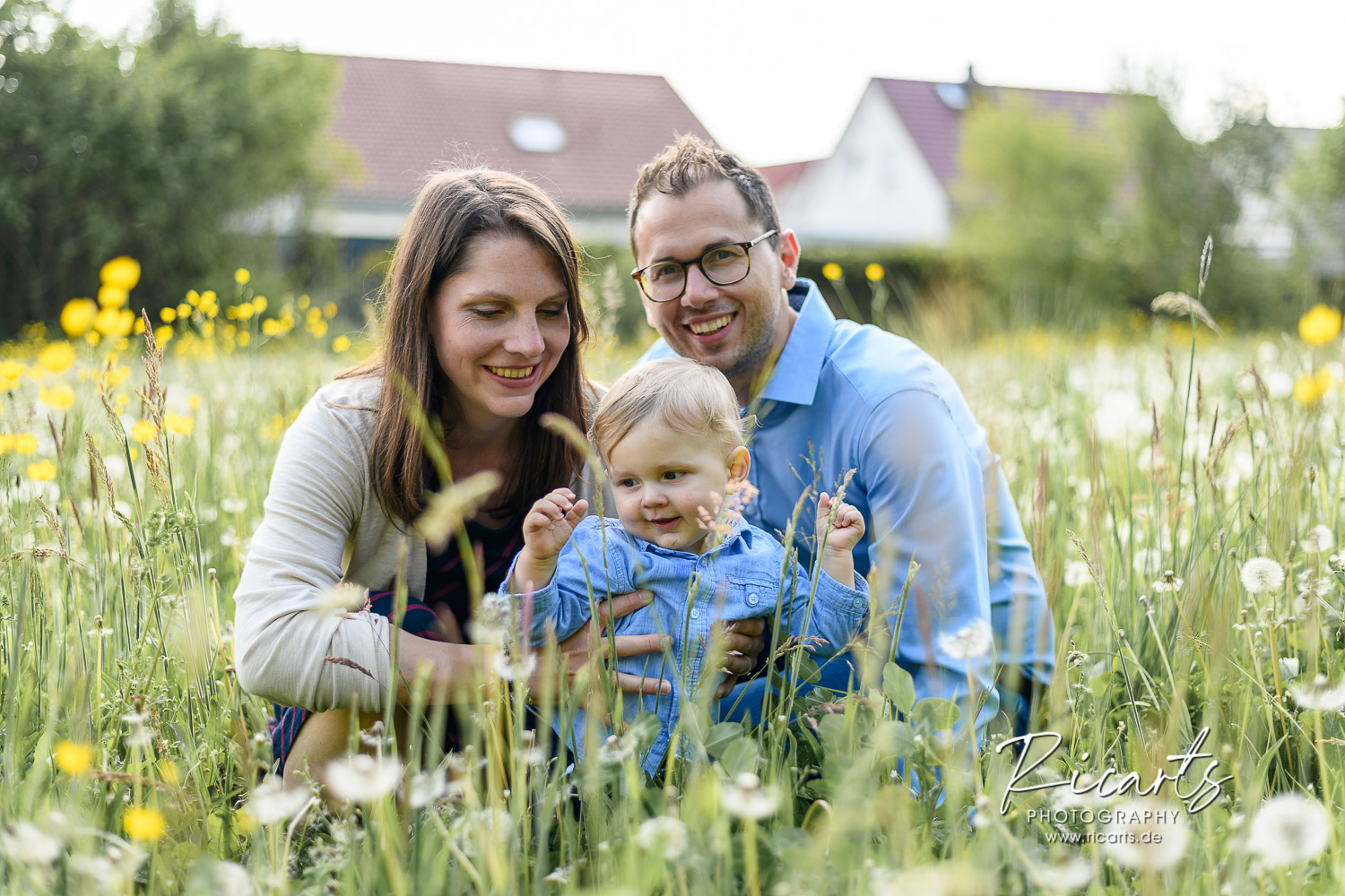 junge-Familie-mit-Kleinkind-sitzt-in-Blumenwiese