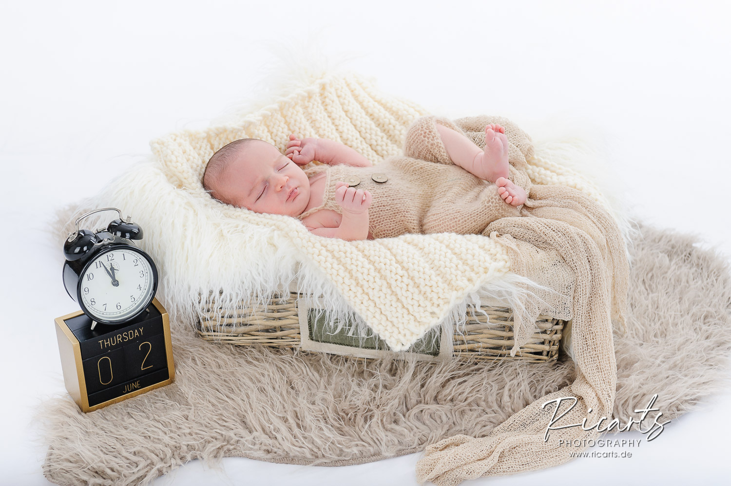 Baby-liegt-in-Körbchen-mit-Deko-Wecker-und-Datumswürfel