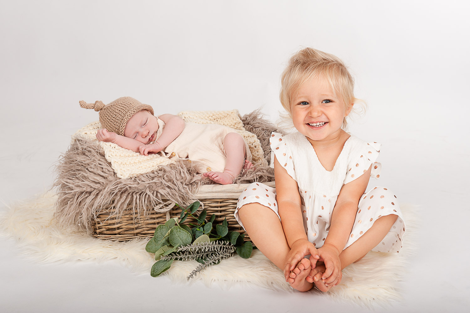 Newborn-Baby-in-Korb-mit-Deko-und-kleiner-Schwester-sitzend