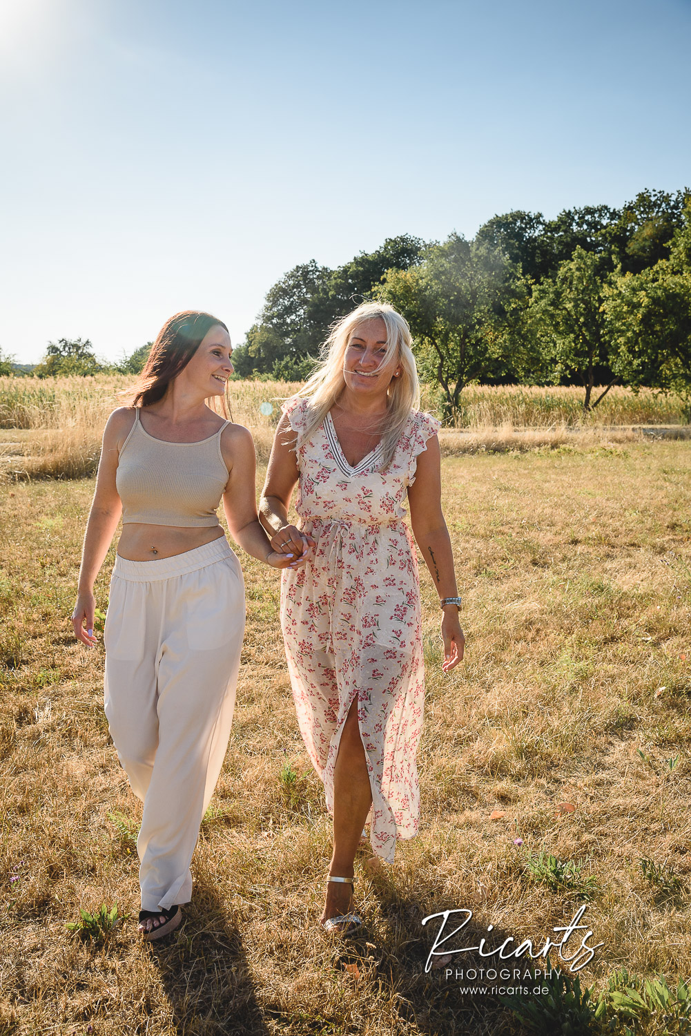 zwei-junge-Frauen-laufen-auf-einer-Wiese-im-Sommer