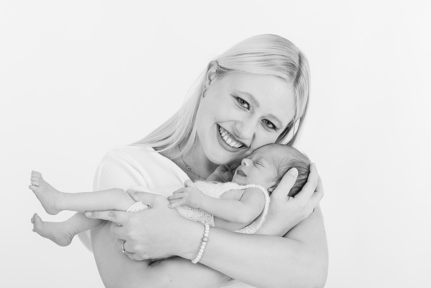 Junge-Mutter-hält-neugeborenes-Baby-im-Arm-und-laechelt-in-Kamera