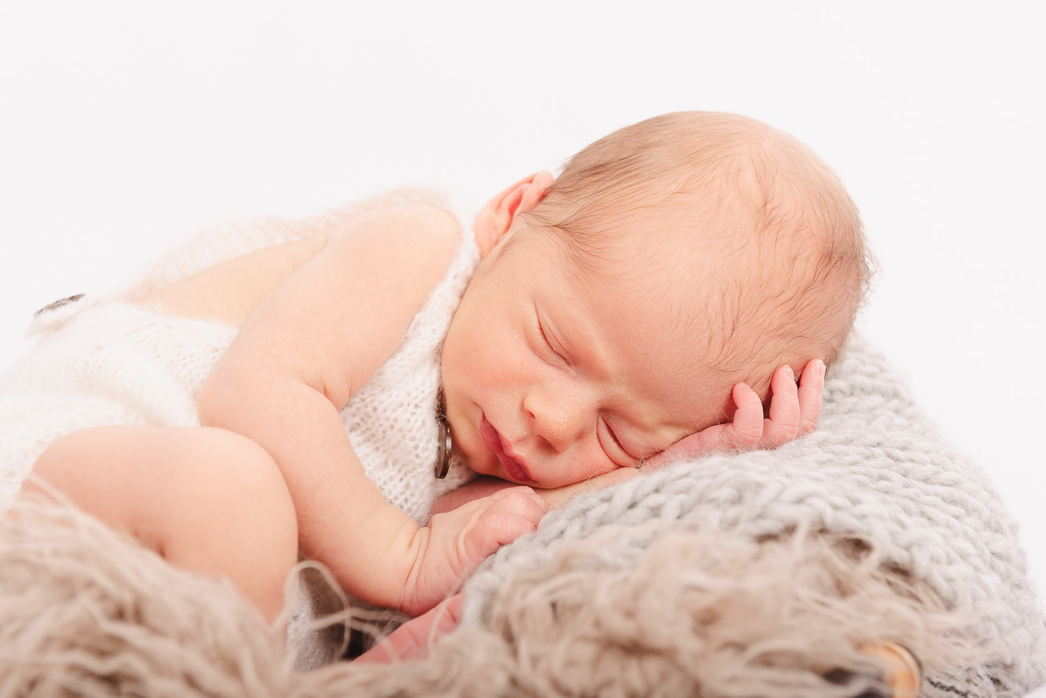Neugeborenes-Baby-liegt-schlafend-in-einem-Korb-und-haelt-die-Hand-an-den-Kopf