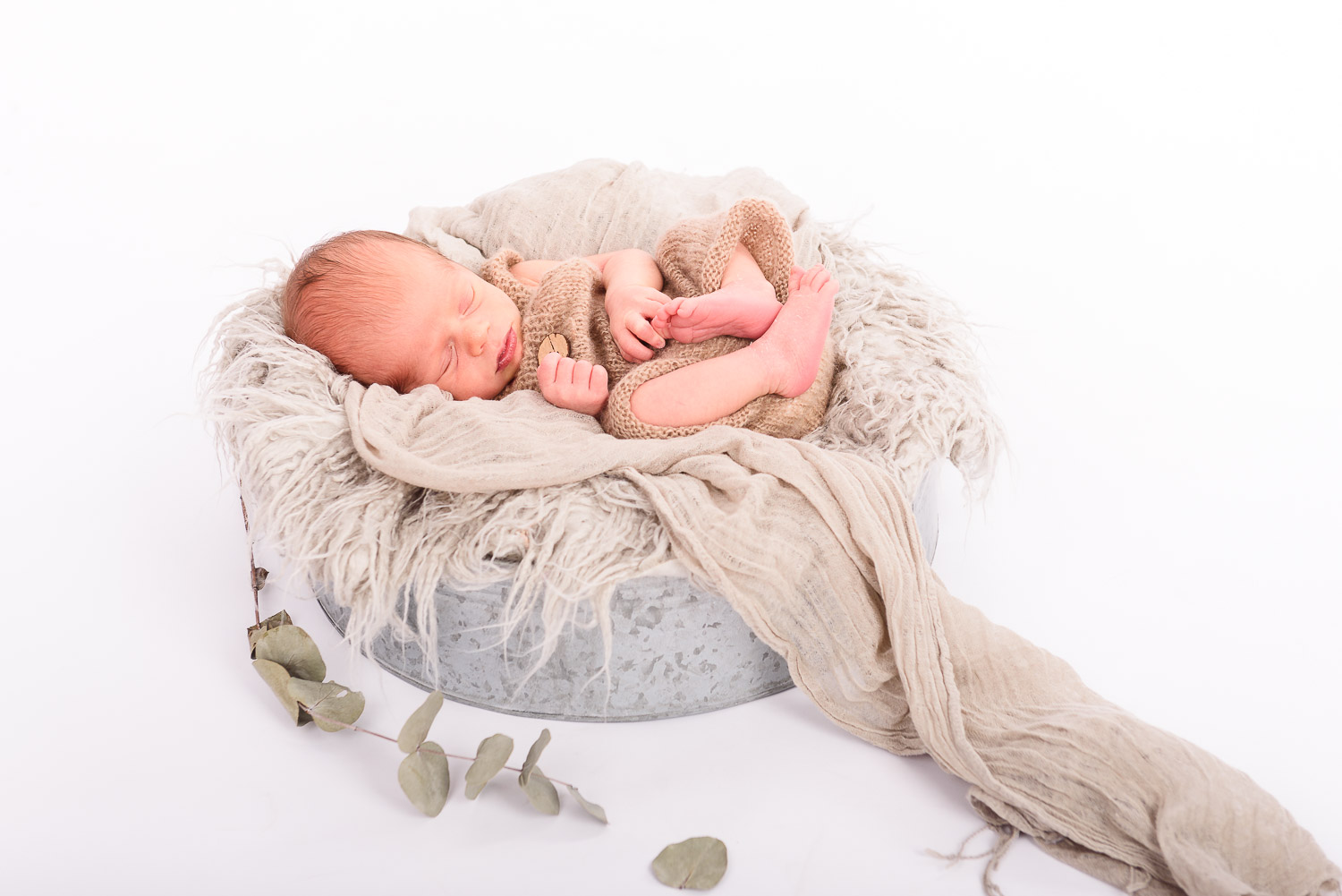 Neugeborenes-Baby-liegt-schlafend-in-einer-Schale-mit-Fell-und-Tuch