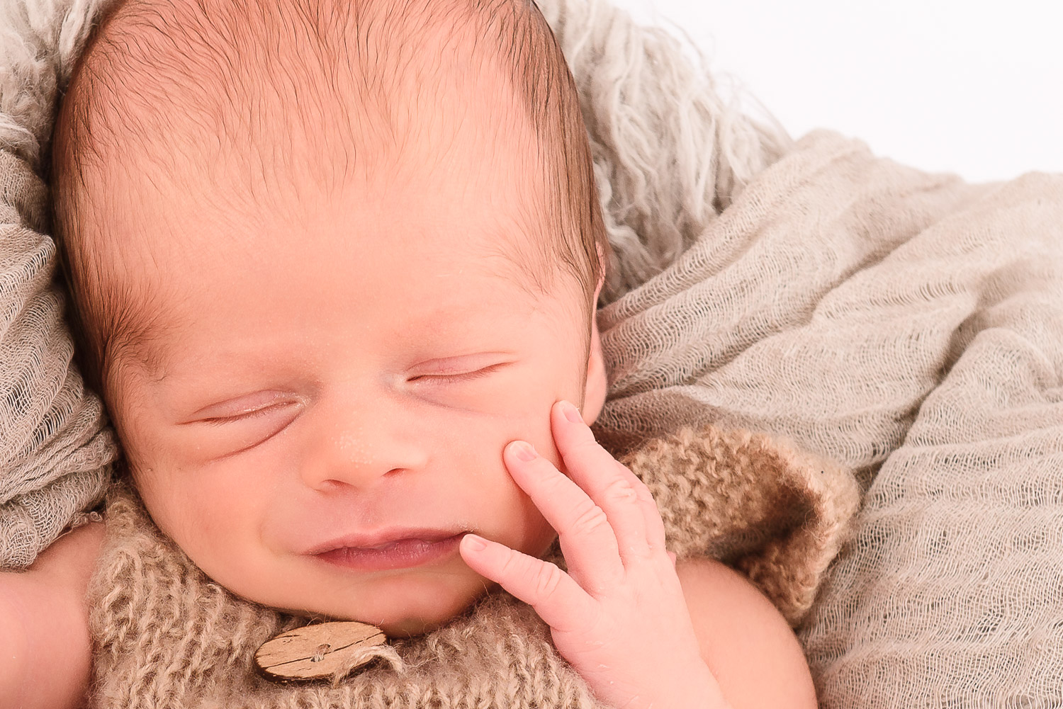 Neugeborenes-Baby-liegt-schlafend-auf-Fell-und-laechelt