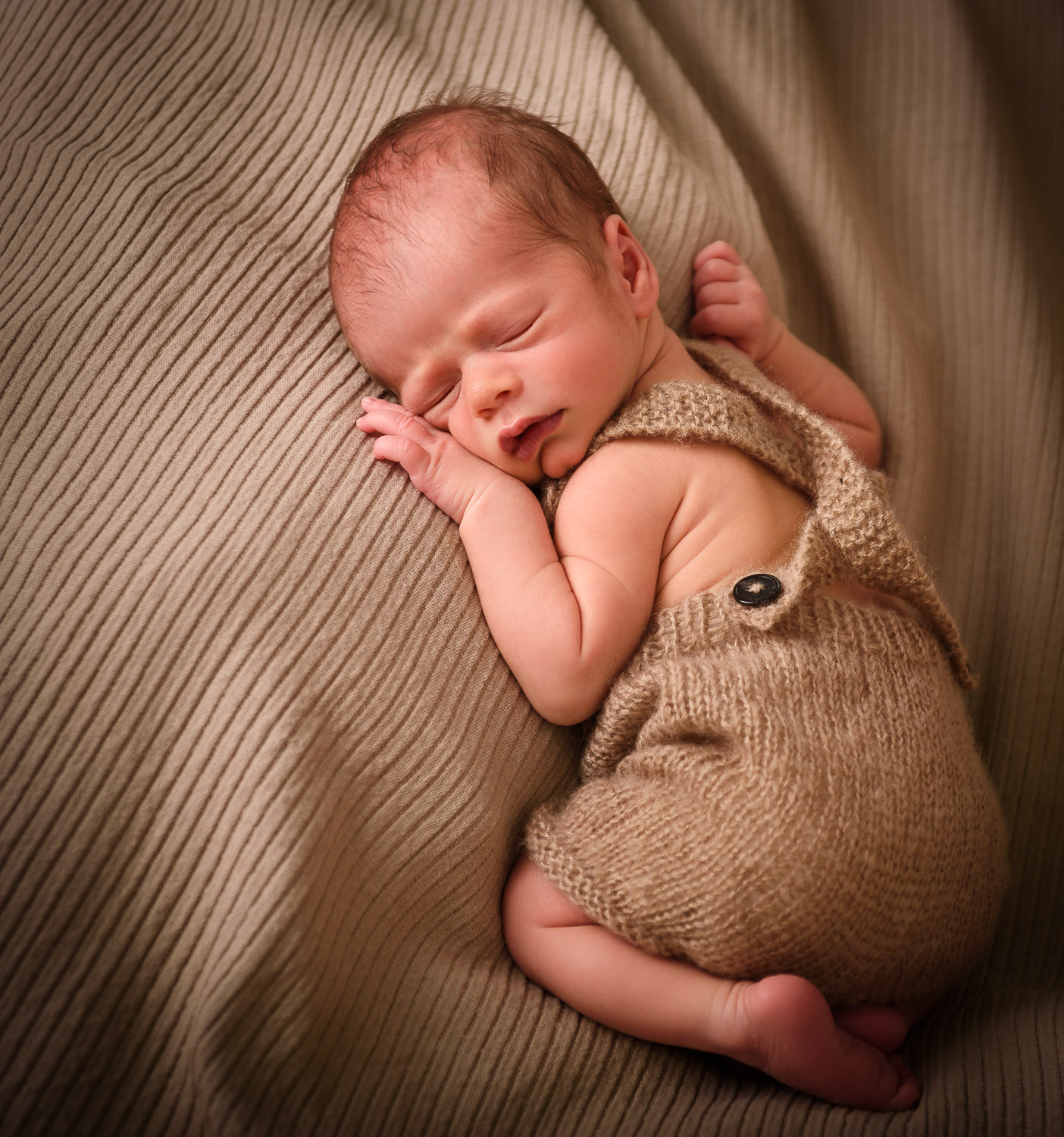 Newborn-Baby-liegt-schlafend-auf-dem-Bauch-auf-einer-Decke