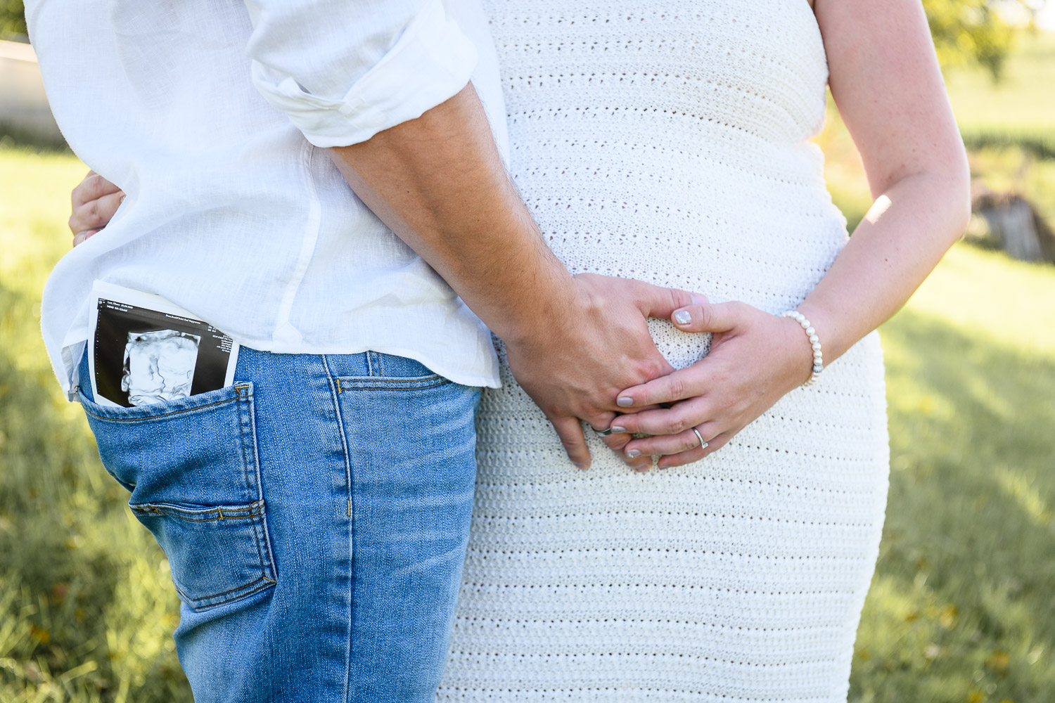 Junges-Paar-schwangere-Frau-im-Sommerkleid-halten-die-Haende-auf-den-Schwangerschaftsbauch