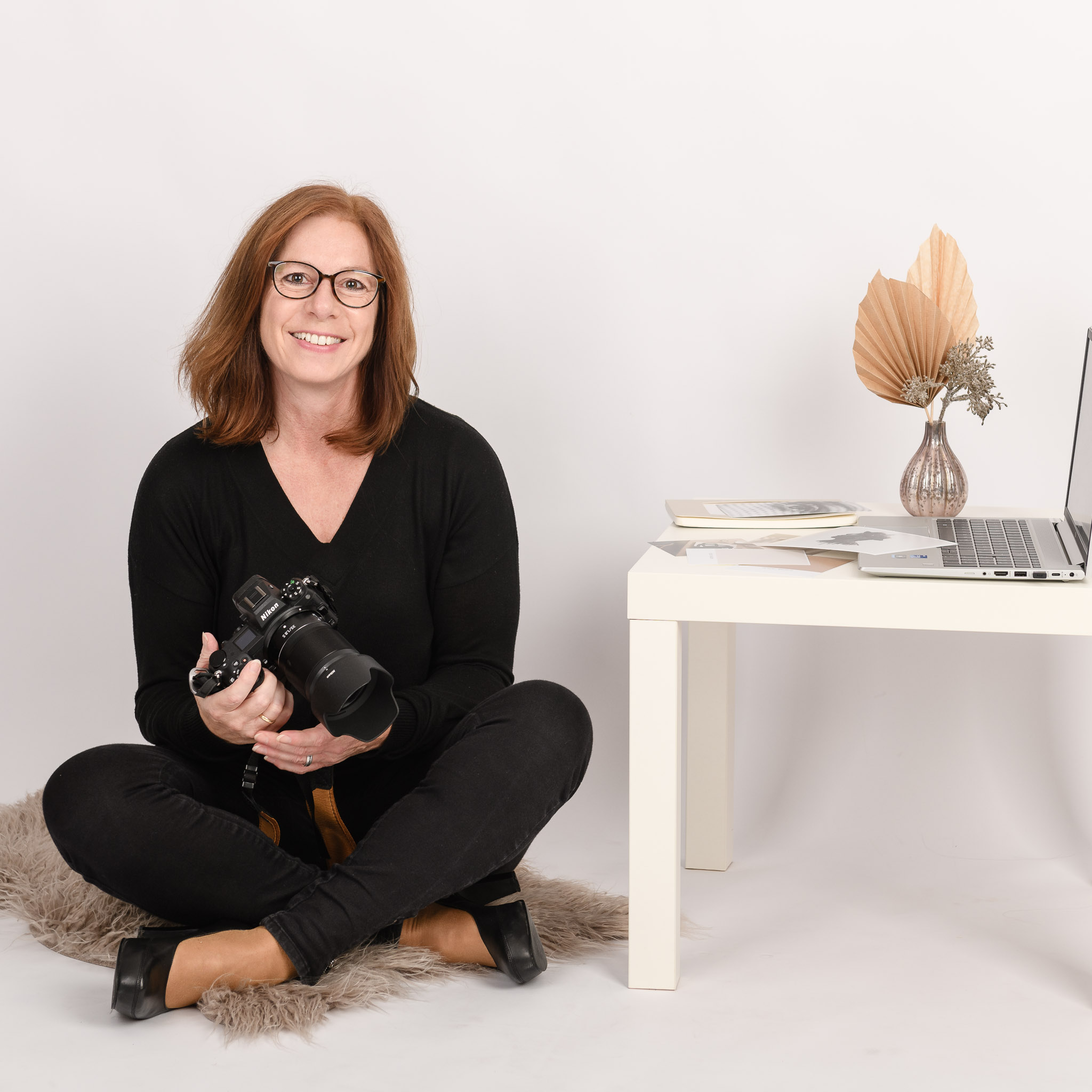 Fotografin-Ricarda Mayer sitzt im Schneidersitz auf einem Fell mit Kamera in der Hand
